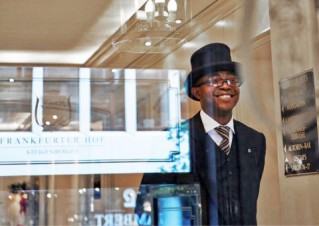 A Deutsche Hospitality employee wearing a suit and top hat at the luxurious hotel Frankfurter Hof.