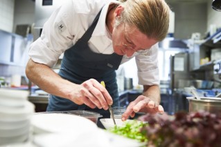 A professional chef is arranging food on a plate.