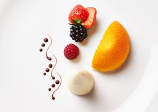 Bunte Früchte, kunstvoll auf einem weißen Teller arrangiert.