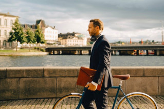 A man pushing his bicycle over a bridge.